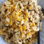 a bowl of crockpot mac and cheese topped with extra Cheddar.