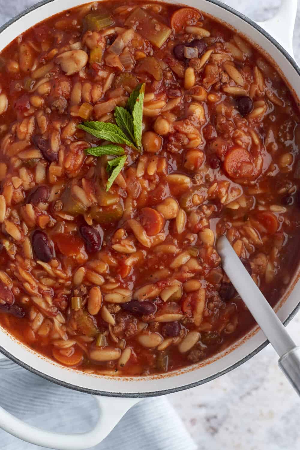 a large pot of pasta e fagioli with a ladle sticking out 