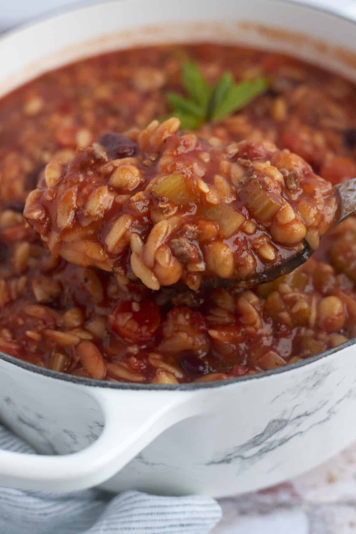 a spoonful of pasta e fagioli being lifted from a pot