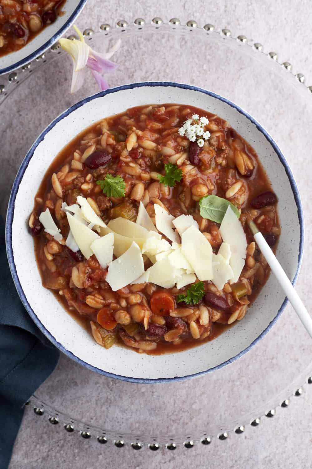 a bowl of pasta and beans soup topped with shaved Parmesan.