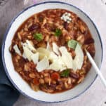 a bowl of Slow Cooker Pasta and Beans Soup (Pasta E Fagioli) topped with Parmesan cheese.