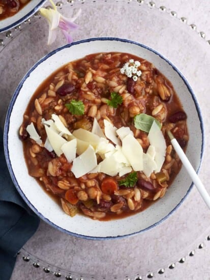 a bowl of Slow Cooker Pasta and Beans Soup (Pasta E Fagioli) topped with Parmesan cheese.