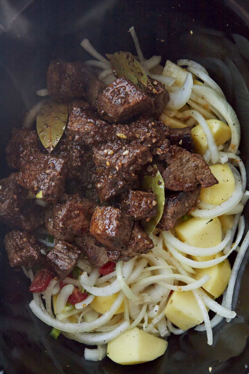 seared beef, onions, potatoes, and spices in a crock pot.