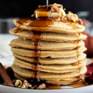 side view of a stack of high protein healthy pumpkin pancakes with maple syrup being drizzled on top