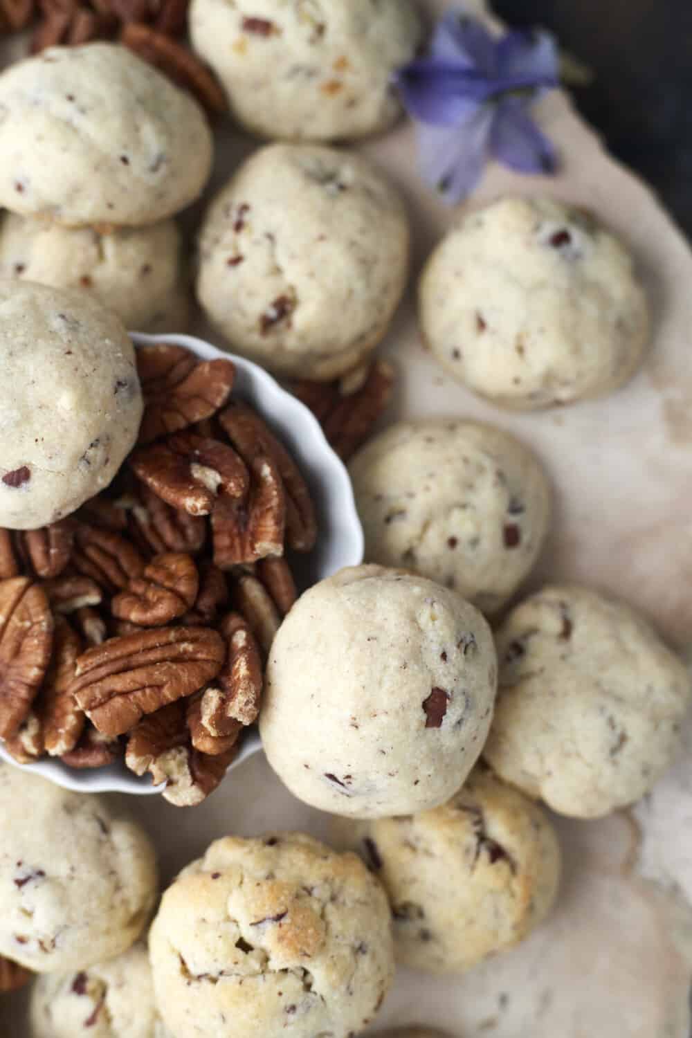 baked pecan Sandies cookies with a small bowl of extra pecans