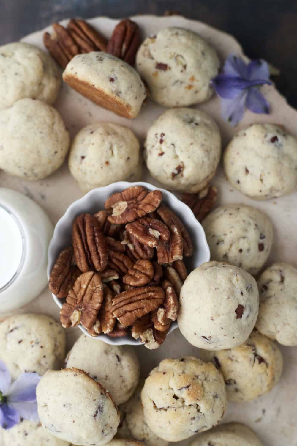baked pecan Sandies cookies with a small bowl of pecans