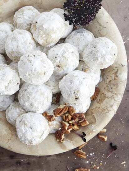 a bowl of pecan snowball cookies with pecans in the bottom