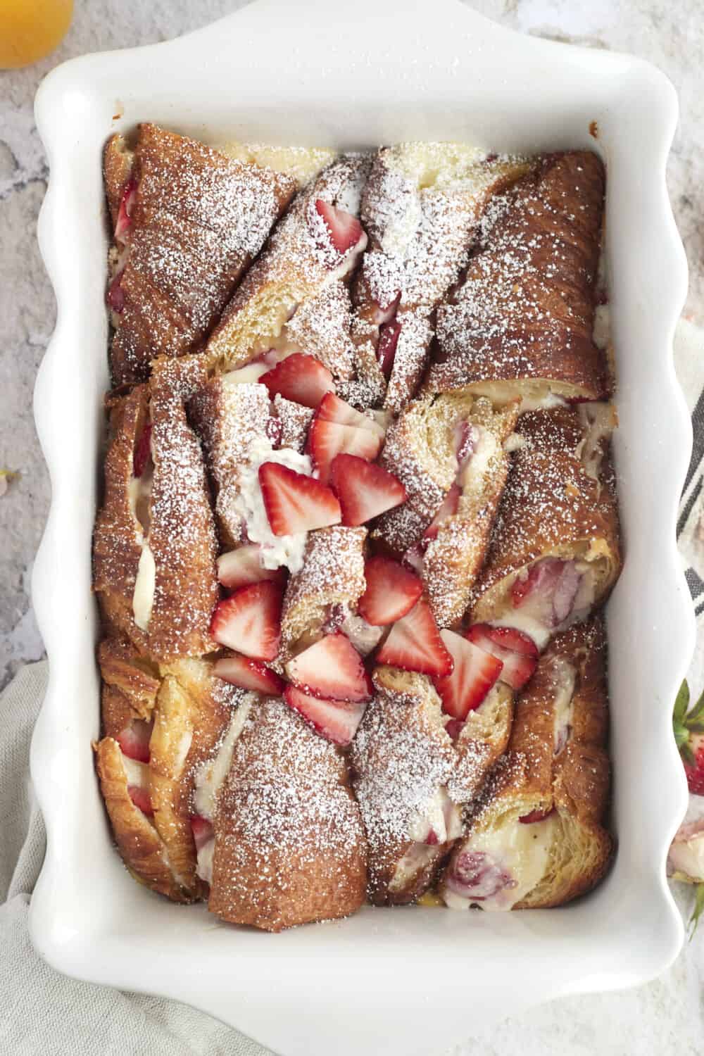 overhead image of strawberry mascarpone in a baking dish topped with strawberry slices and powdered sugar