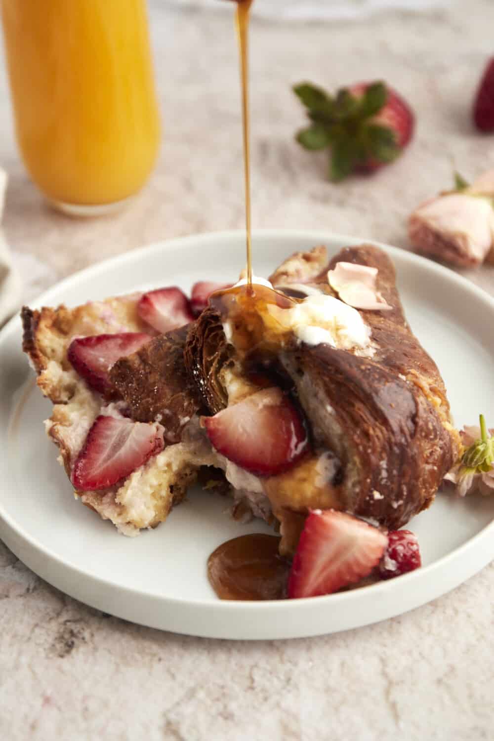 syrup being poured over a serving of strawberry mascarpone french toast on a plate