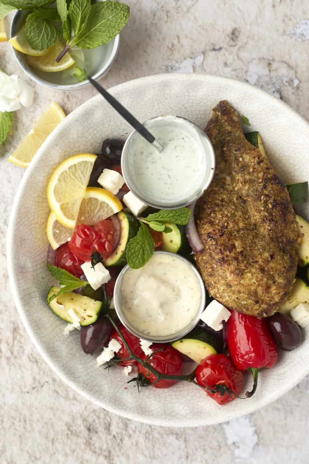 a bowl of za'atar chicken with vegetables and dipping sauce