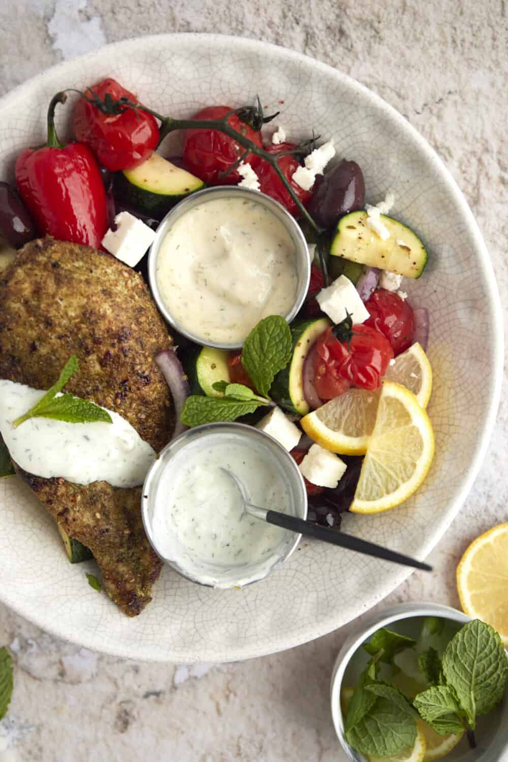 overhead image of a bowl of za'atar chicken with vegetables and a yogurt sauce