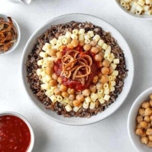 overhead large bowl of koshari with the fixings on top and the sides
