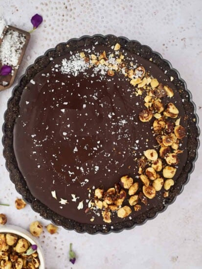 A whole chocolate tart topped with candied hazelnuts and sea salt.