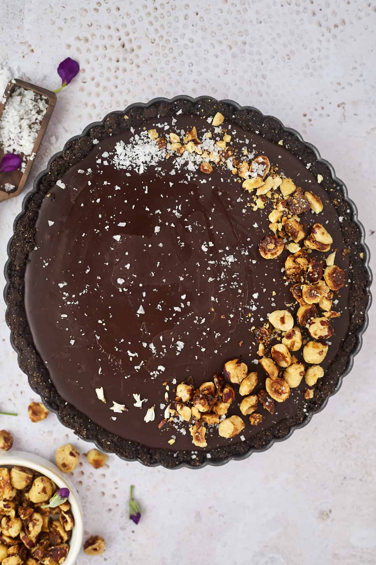 a whole chocolate tart topped with candied hazelnuts and sea salt