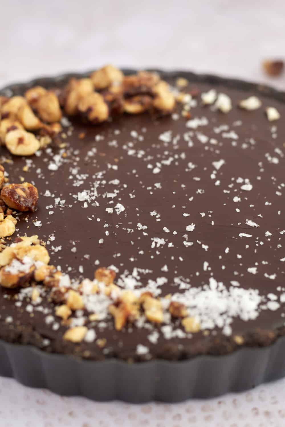 a tart with chocolate filling topped with hazelnuts and salt
