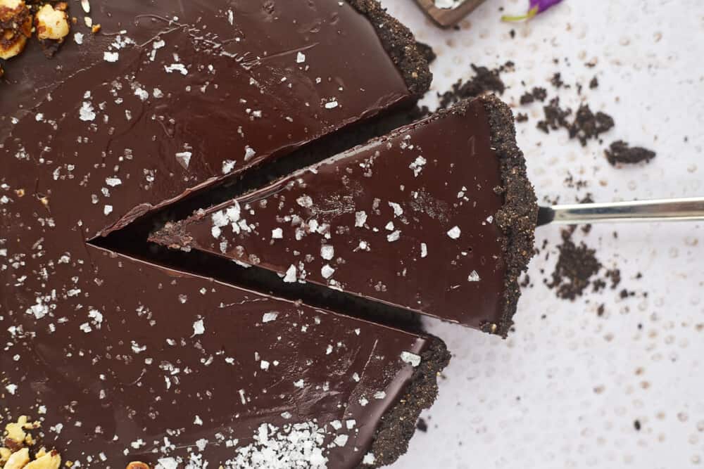 a piece of chocolate tart being sliced from the entire tart