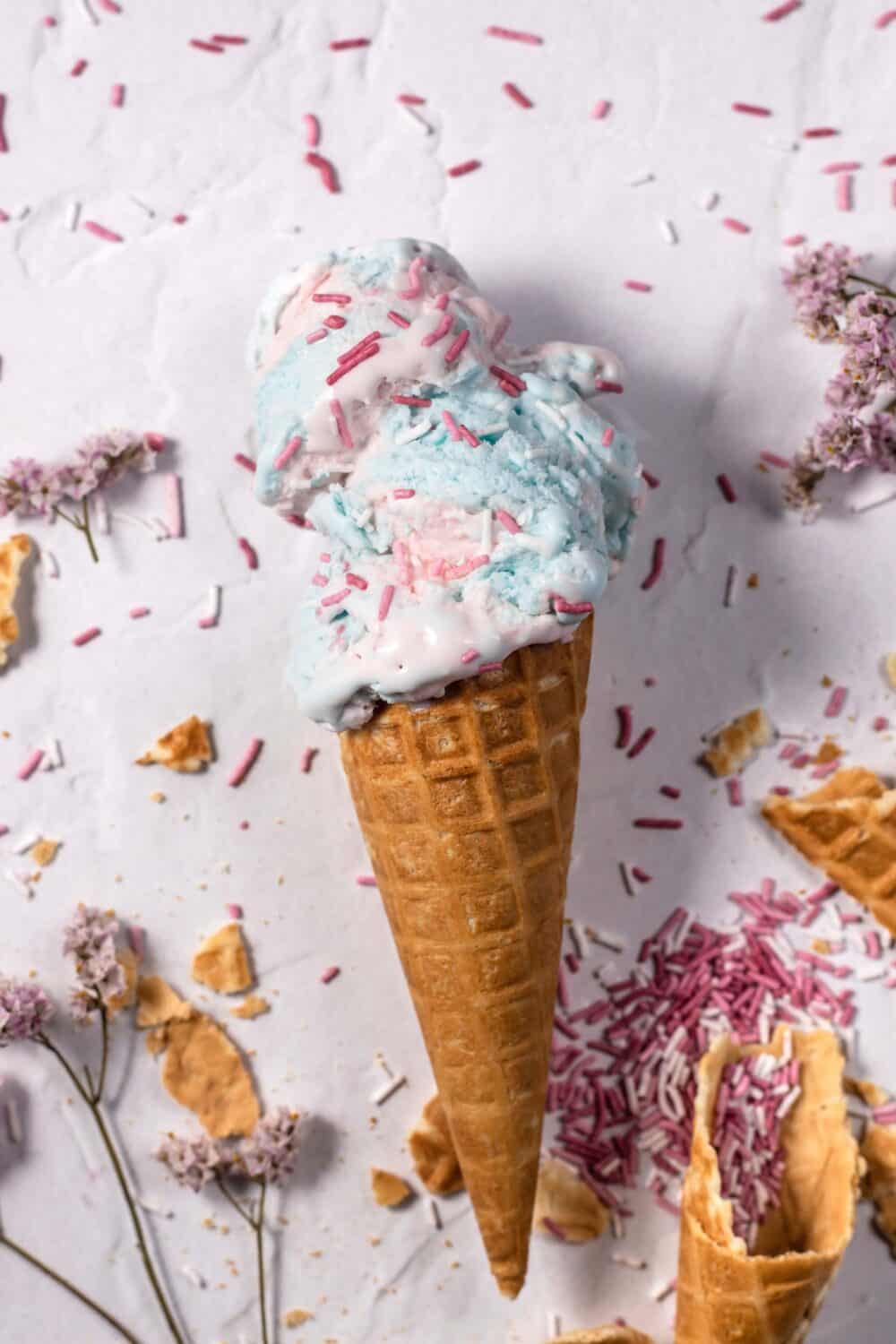 an ice cream cone full of homemade cotton candy ice cream topped with sprinkles