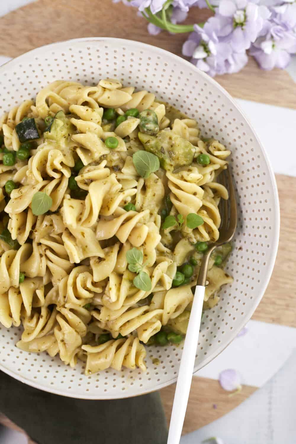 a bowl of creamy pesto pasta with a fork sticking out