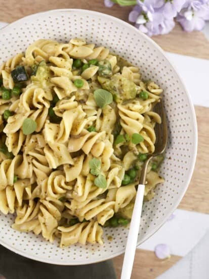a bowl of creamy pesto pasta with veggies