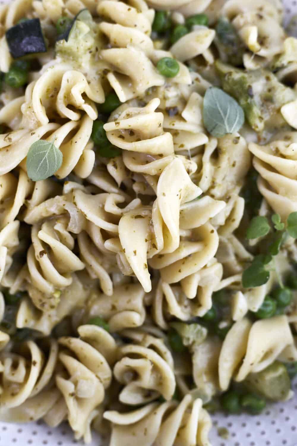 close up image of creamy pesto pasta with asparagus, zucchini, and peas