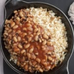 a skillet of vermicelli rice topped with black-eyed pea stew
