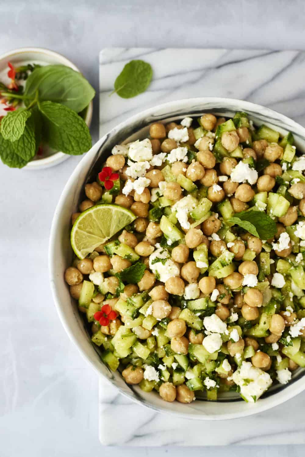 a bowl of chickpea cucumber feta salad topped with a lime wedge