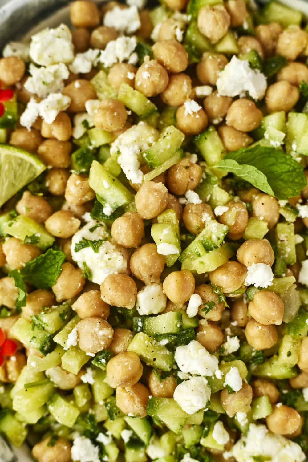 close up image of chickpeas, cucumber, herbs, and feta