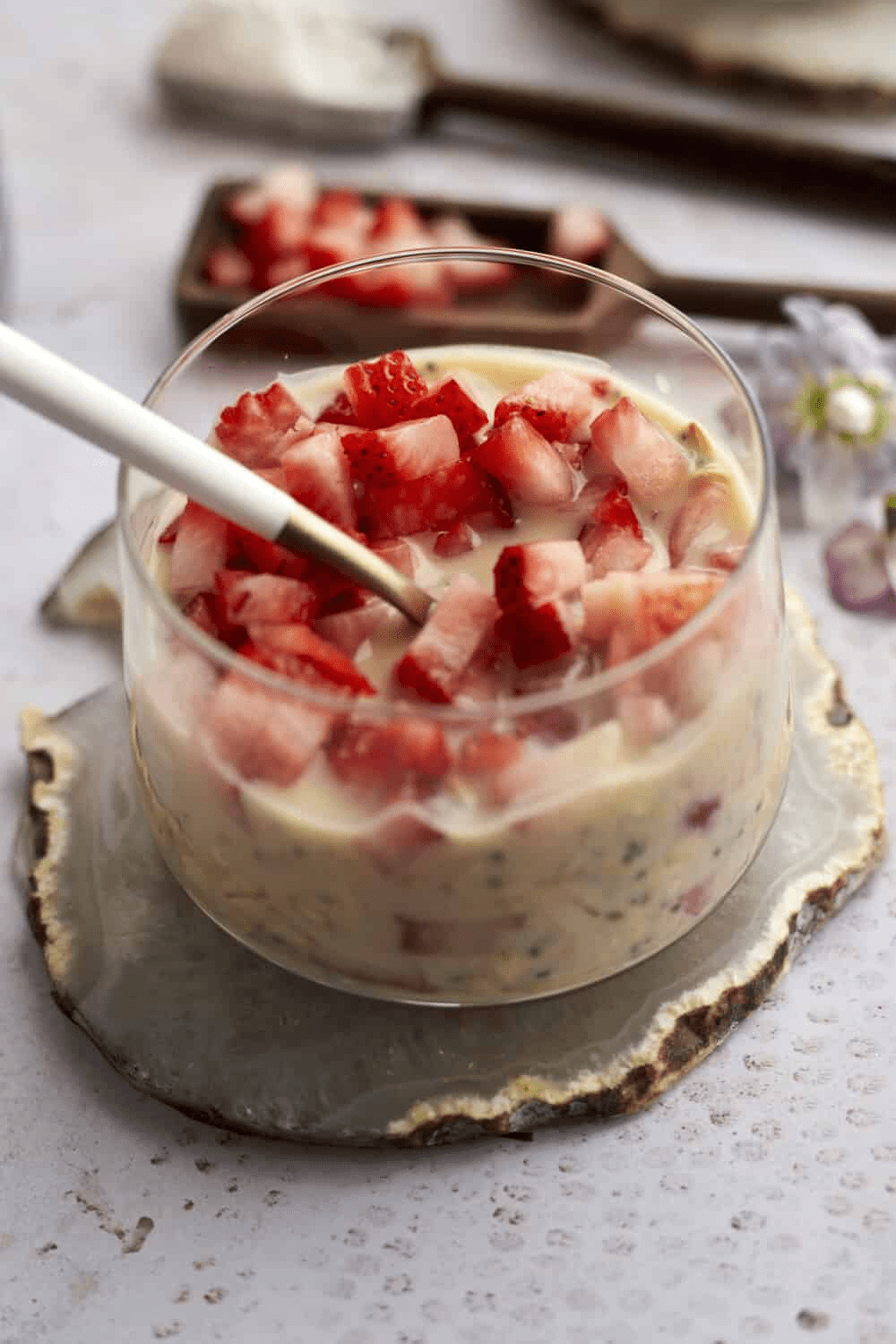 strawberry overnight oats in glass on counter with board of strawberries