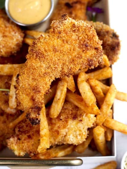 chicken tenders on a baking tray with fries