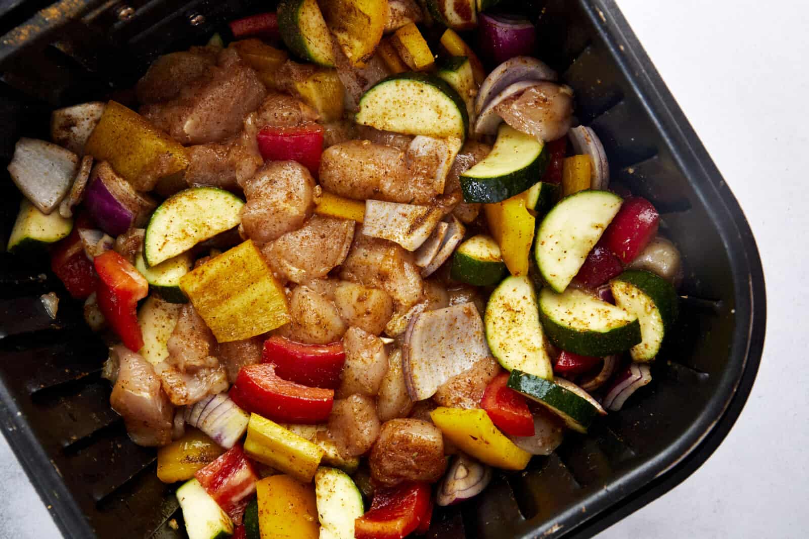 raw chicken and vegetables in an air fryer