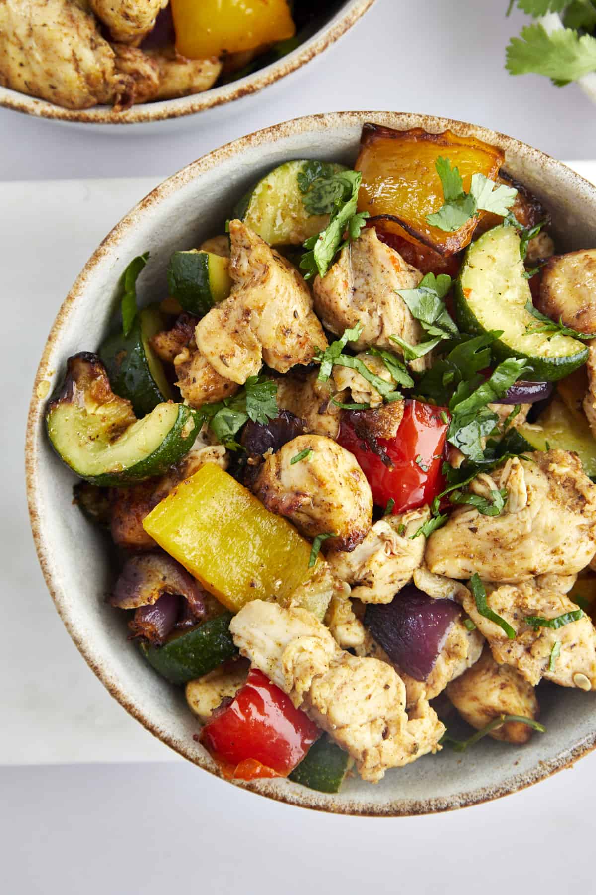 a bowl of air fryer chicken breast with vegetables topped with fresh herbs