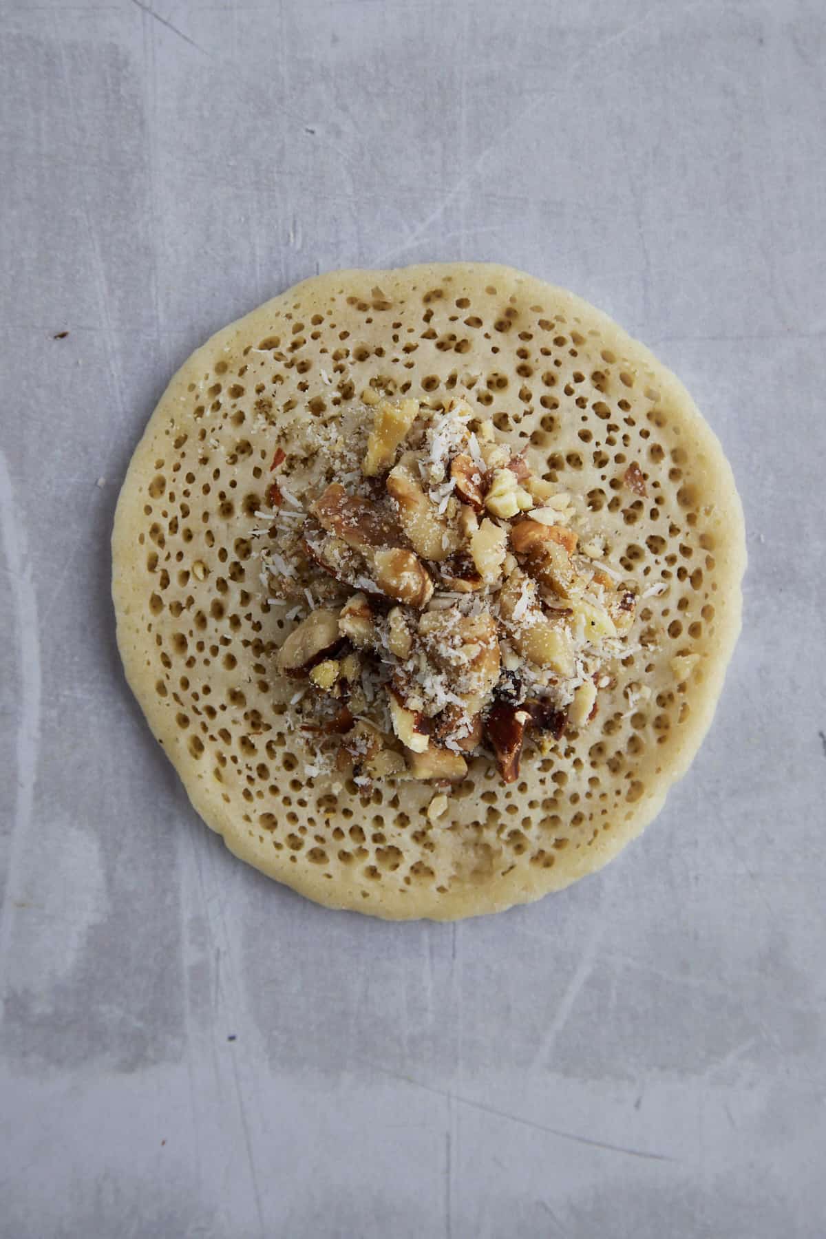a mixture of chopped nuts and sugar in the center of a qatayef pancake