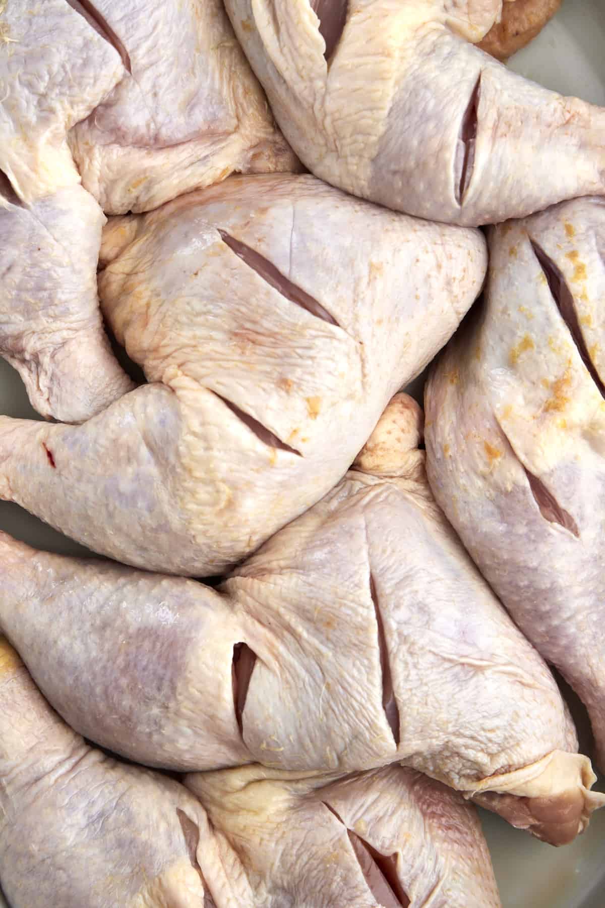 raw chicken legs with slices in them