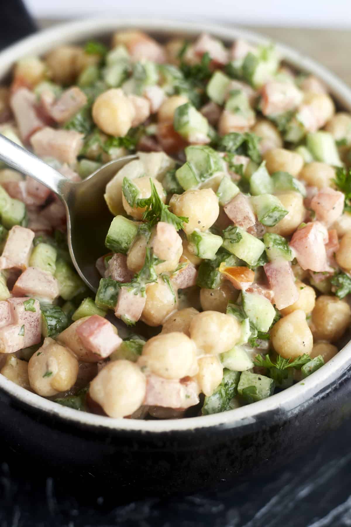 a spoonful of chickpeas, cucumbers, and tomatoes tossed with a tahina dressing