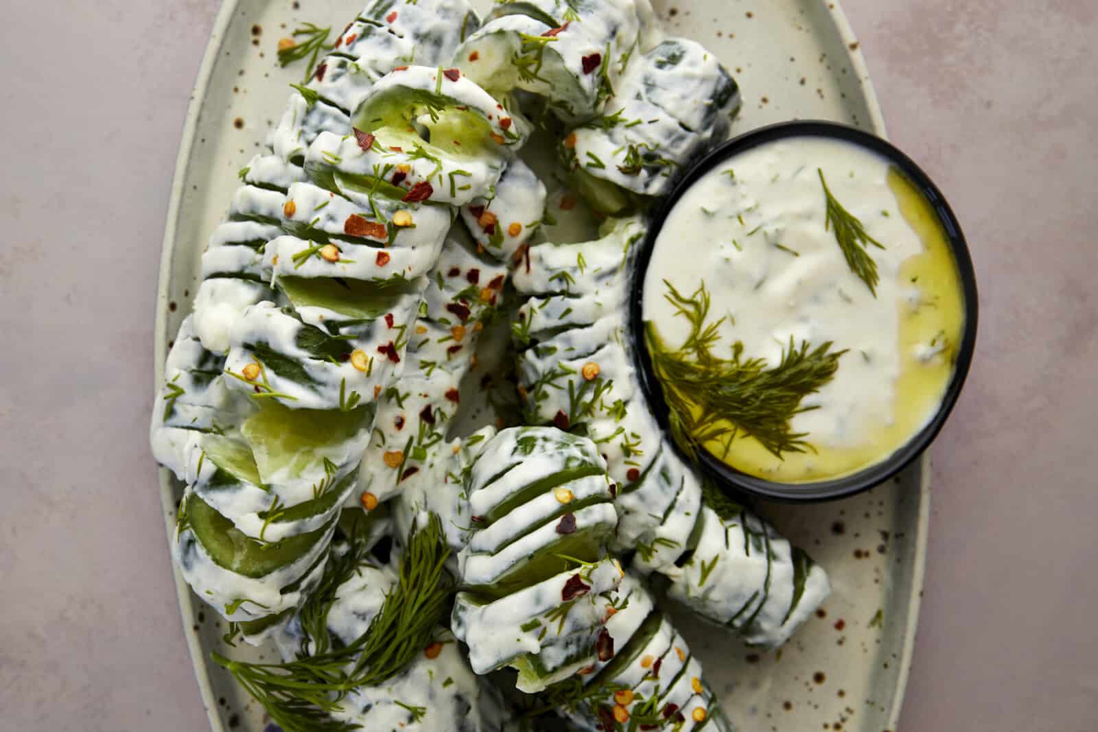 a platter of spiraled cucumber yogurt salad with extra yogurt sauce on the side