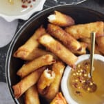 a basket of fried feta rolls with a bowl of hot honey