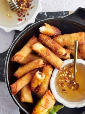 a basket of fried feta rolls with a bowl of hot honey
