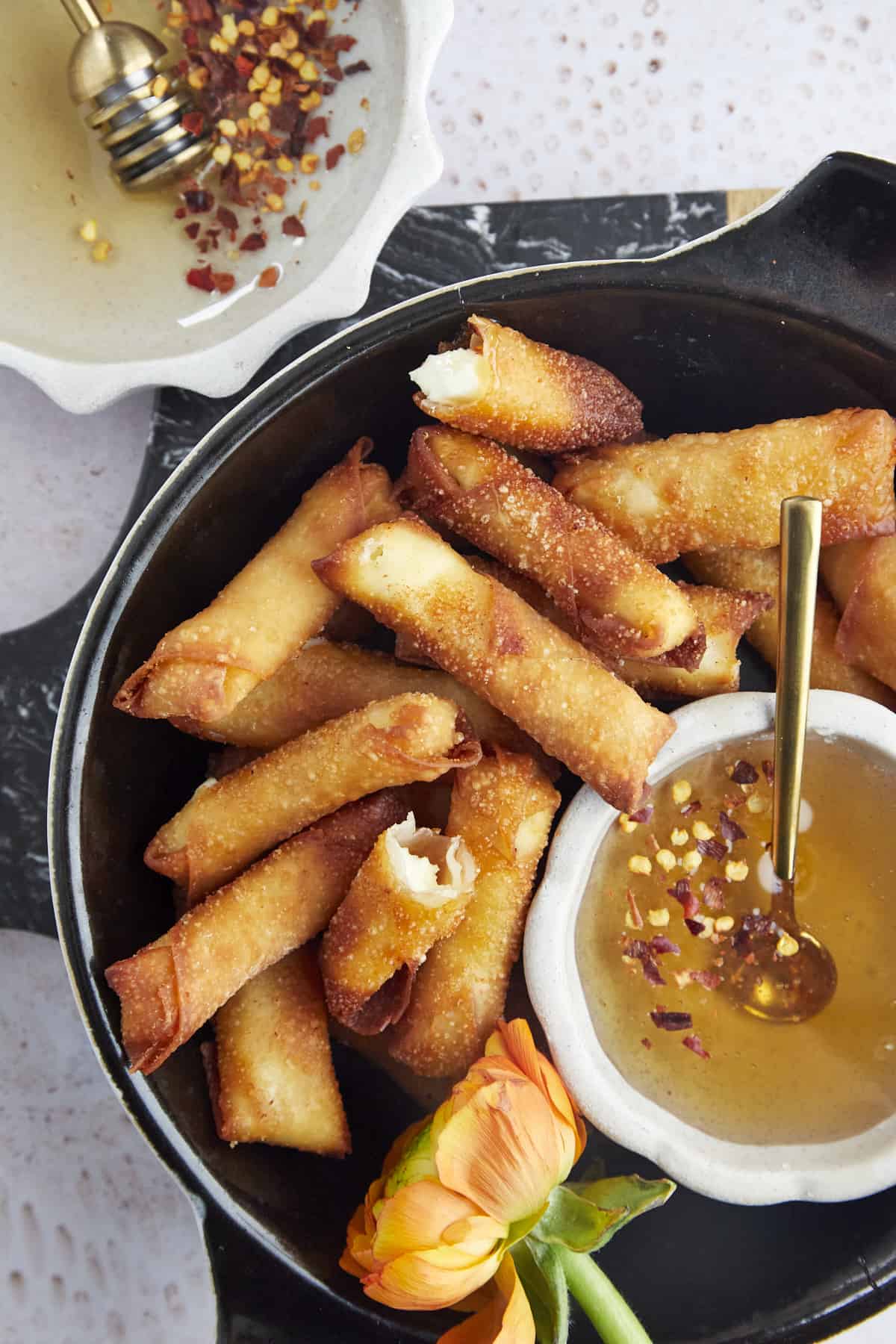 a basket of fried feta rolls with hot honey in the center