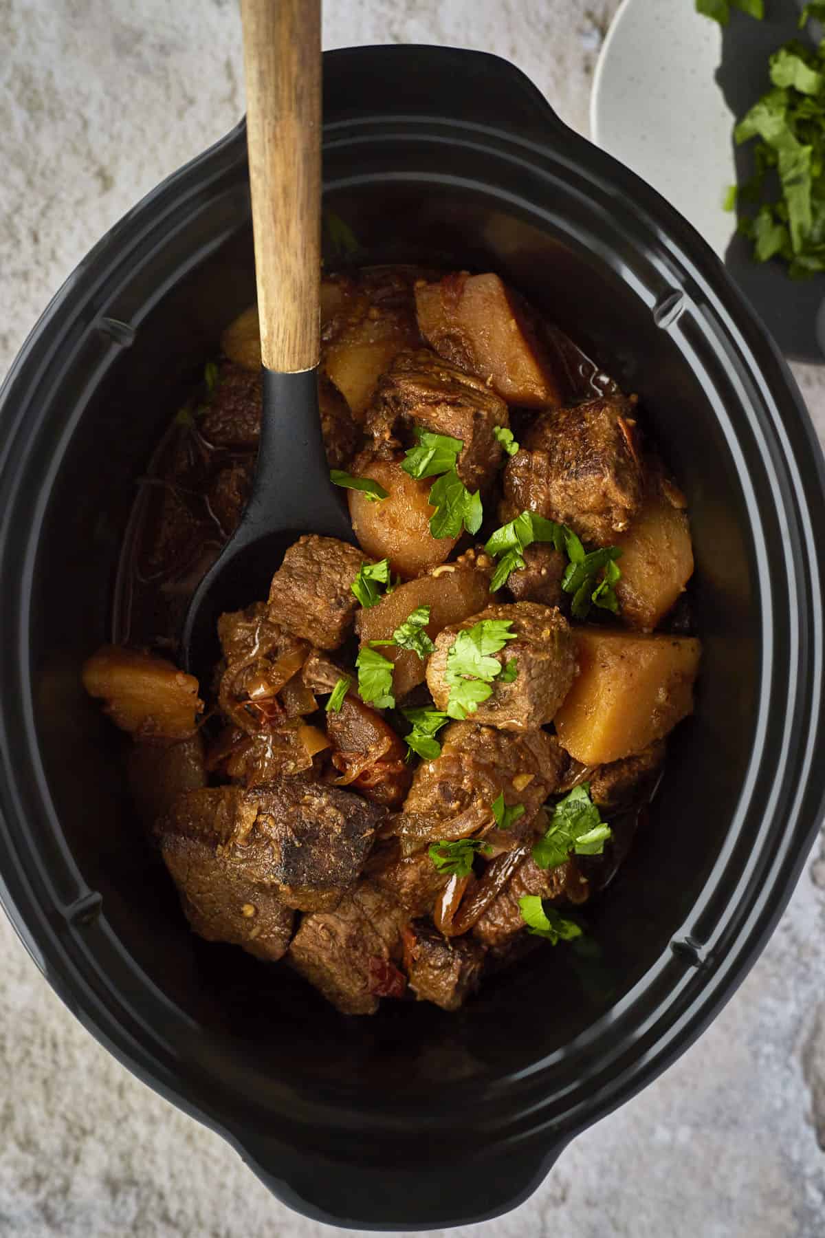 Cooked beef stew with potatoes in a crockpot. 