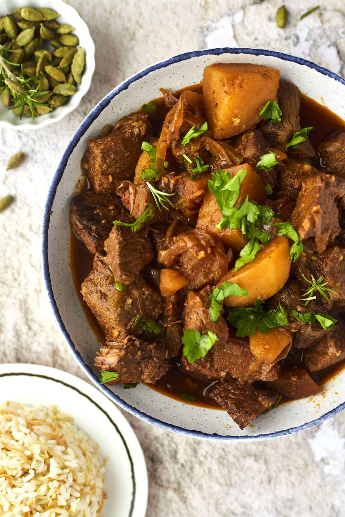 A bowl of beef stew topped with parsley. 