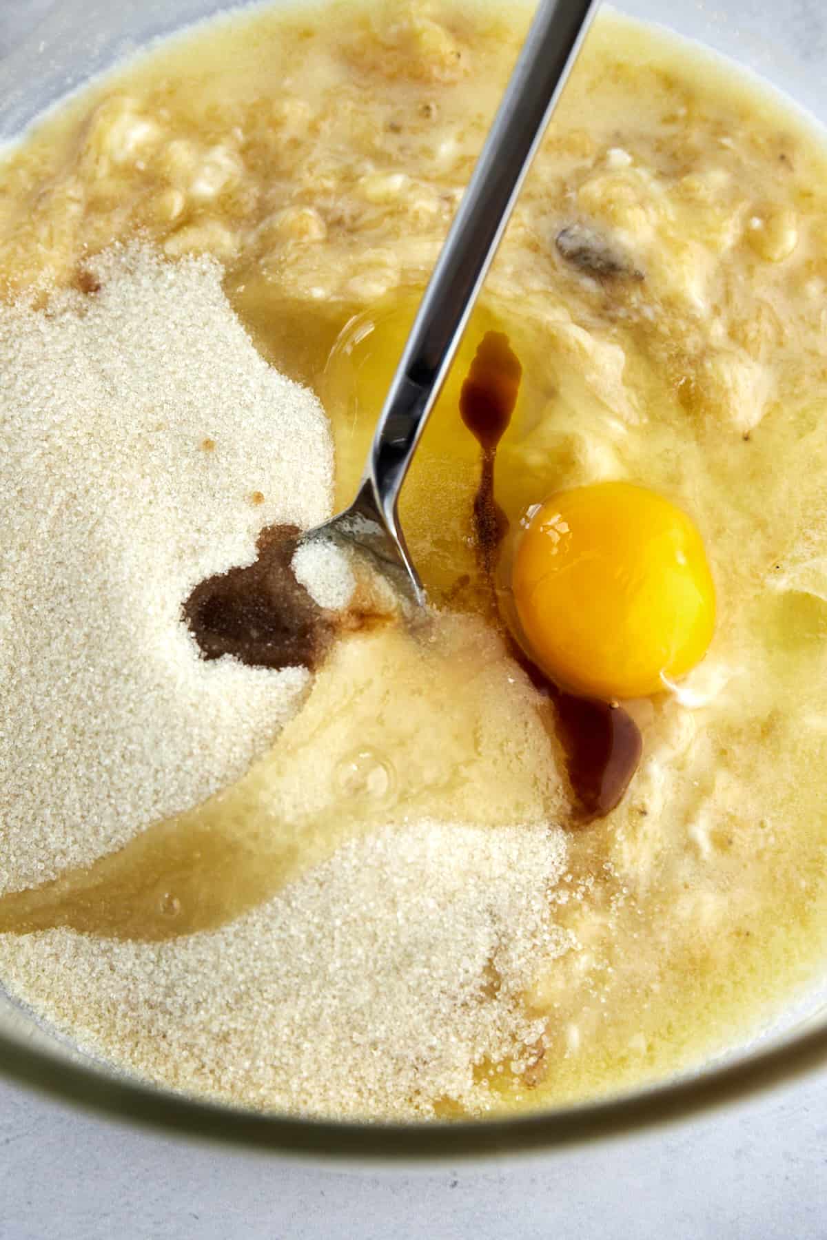 eggs, vanilla, and sugar being stirred into banana bread