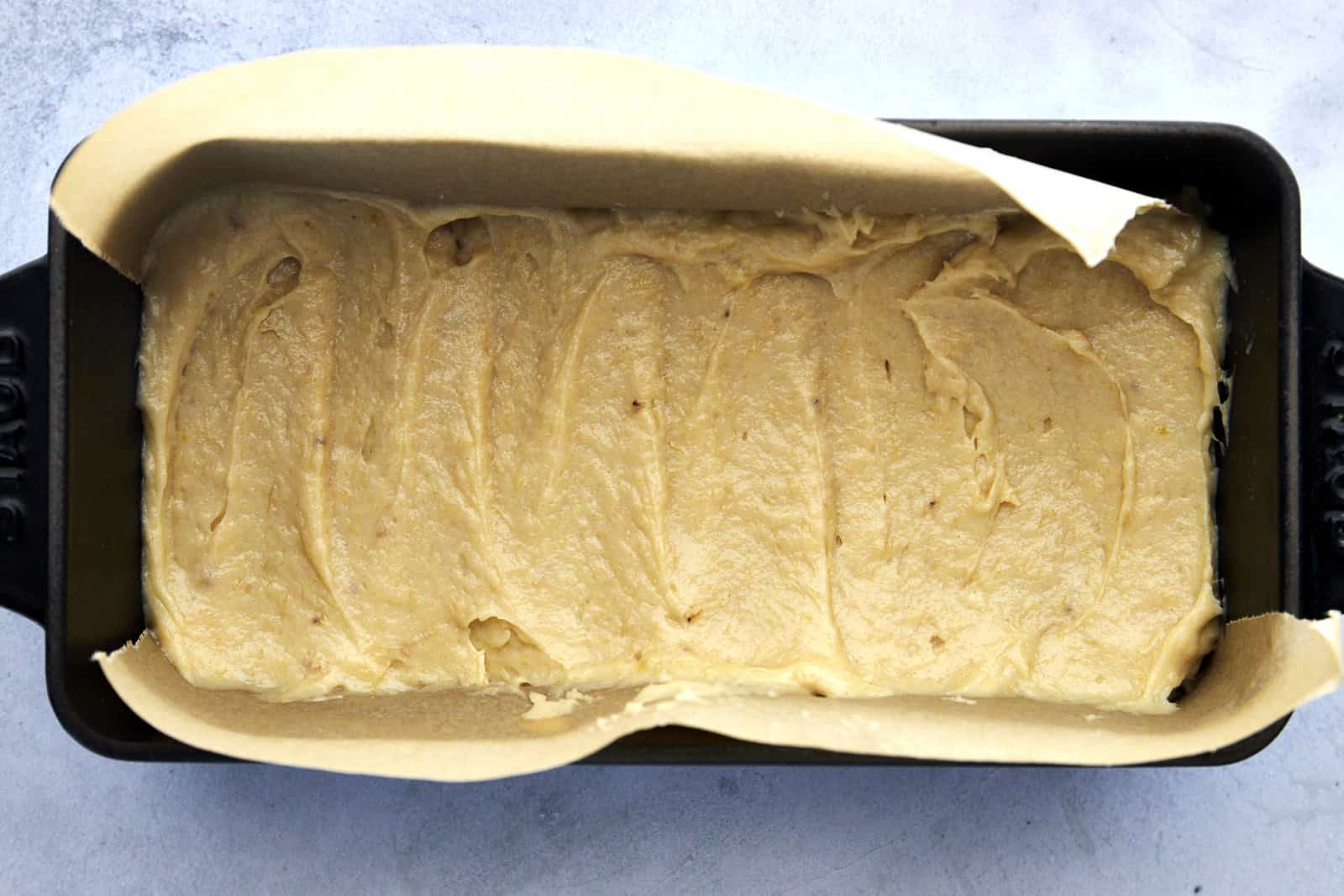 a parchment paper-lined baking sheet full of unbaked banana bread batter