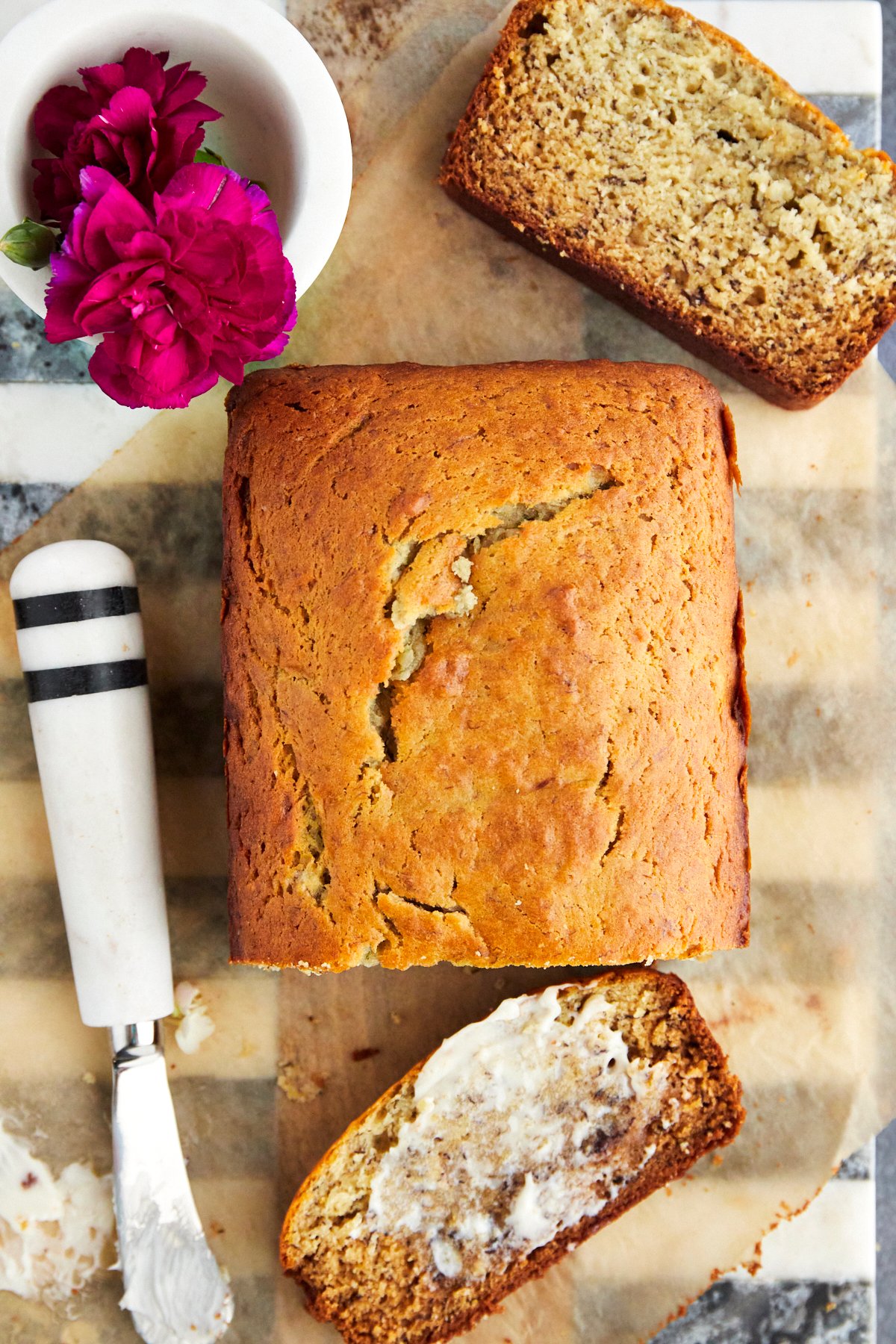 a loaf of one bowl banana bread with a slice cut and butter smeared on top 