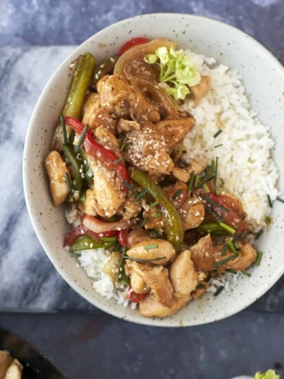 a bowl of white rice topped with black pepper chicken stir fry