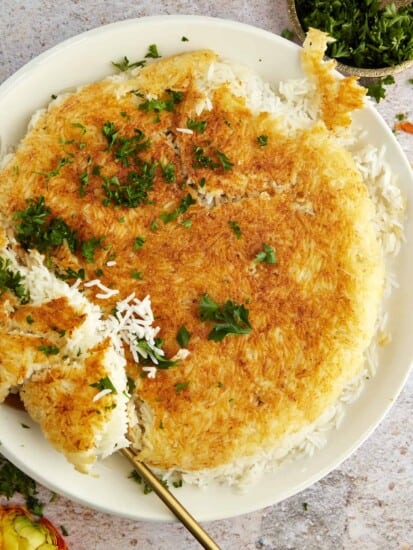 Persian rice on a serving platter with a portion being lifted with a spoon