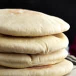 a stack of 4 white pita bread pockets on a plate.