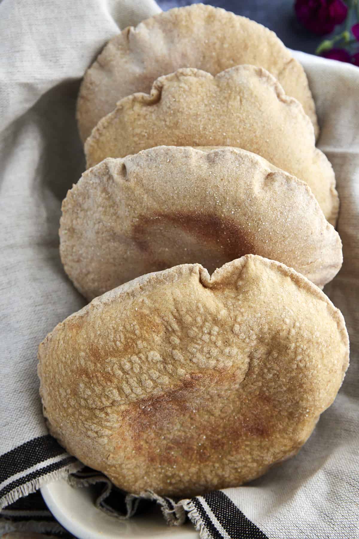 four whole wheat pita bread pockets in a basket
