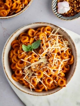 a bowl of homemade spaghetti o's topped with fresh Parmesan and basil