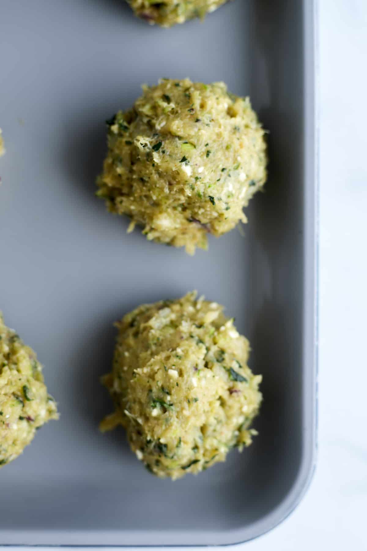 raw Greek meatballs on a baking sheet