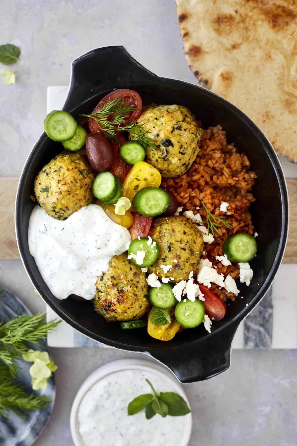 Greek meatballs over rice topped with cucumber, tomatoes, and tzatziki